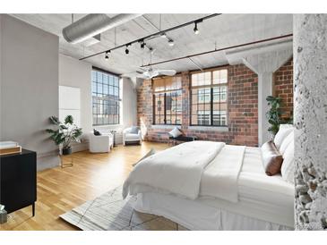 Bright bedroom features exposed brick, concrete ceilings, and large windows with city views at 1863 Wazee St # 6E, Denver, CO 80202