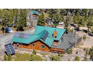 Aerial view of a house featuring a well-maintained deck and solar panels, nestled among lush green trees at 14800 Gold Hill Rd, Boulder, CO 80302