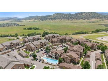 Scenic aerial view of apartment complex featuring a pool, parking, and mountain views at 10062 W Victoria Pl # 205, Littleton, CO 80127