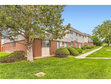 Charming townhouse with red brick and lush green lawn with walkway and mature trees in a well-maintained community at 8613 Santa Fe Dr, Thornton, CO 80260