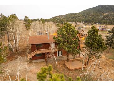 Charming two-story home with a wooden deck and a rustic outdoor living space surrounded by trees at 26167 De Berry St, Conifer, CO 80433