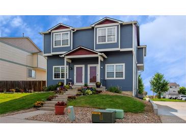 Charming blue townhome with landscaped front yard and colorful flowerbeds leading to the entrance at 711 Elm St, Frederick, CO 80530