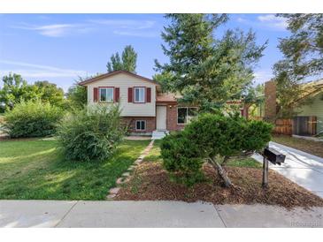 Charming home with a well-manicured lawn, mature trees, and a welcoming facade on a sunny day at 8952 W Stanford Ave, Denver, CO 80123