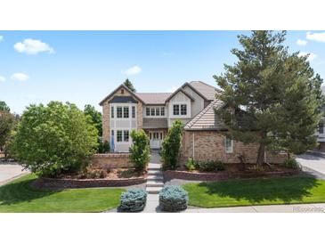 Charming two-story home with manicured lawn, mature trees, and brick accents at 9232 Rockport Ln, Highlands Ranch, CO 80126