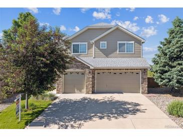 Two-story home boasts a two-car garage, mature landscaping, and a well-maintained lawn under a bright, blue sky at 1022 Orion Way, Castle Rock, CO 80108