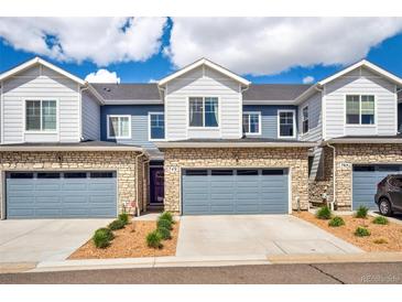 Inviting townhome showcasing a stone facade, blue siding, and attached garages at 749 Bishop Pine Way, Castle Rock, CO 80104