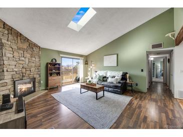 Inviting living room boasts a cozy stone fireplace, vaulted ceiling with skylight, and sliding glass door to balcony at 430 Zang St # 4-301, Lakewood, CO 80228