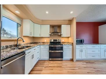 Bright kitchen features granite countertops, stainless steel appliances, and white cabinetry at 2446 S Vaughn Way # A, Aurora, CO 80014