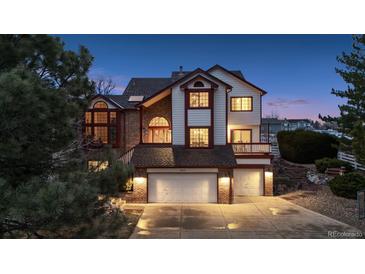 Charming two-story home with a brick and white facade, two-car garage, and professionally landscaped yard at 15935 W 77Th Pl, Arvada, CO 80007