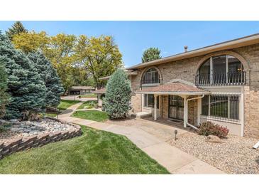 Charming brick townhome featuring arched windows, iron railings, covered porch, and well-maintained landscaping at 3210 S Oneida Way, Denver, CO 80224