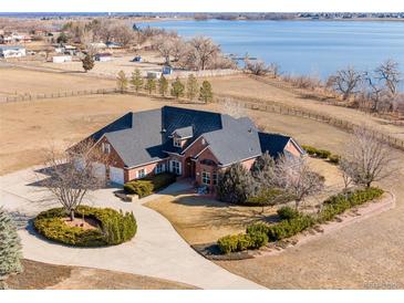 Stunning aerial view of brick home with a circular driveway, lush landscaping and lake views at 2366 Shoreside Dr, Berthoud, CO 80513