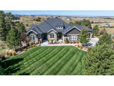 Beautiful home featuring a manicured lawn, stone accents, and a welcoming front porch with chairs at 9563 Red Primrose St, Franktown, CO 80116