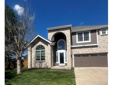 Charming two-story home with arched entryway, beautiful brickwork, and well-manicured lawn at 16519 E Hialeah Dr, Centennial, CO 80015