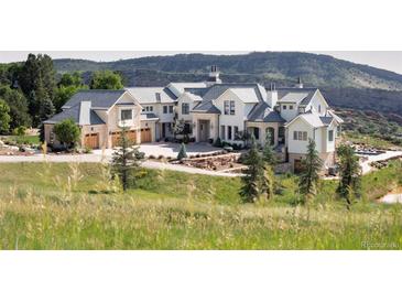 Expansive luxury home boasting stone accents, neutral paint, three-car garage, and mountain views at 9356 Cherrywood Trl, Littleton, CO 80127
