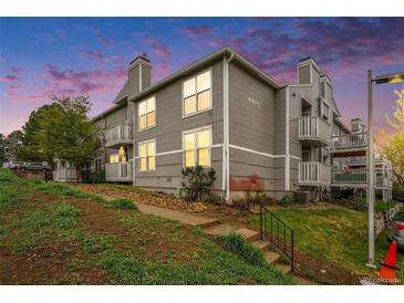 Exterior view of gray apartments featuring private balconies and landscaped front yard at 4460 S Pitkin St # 119, Aurora, CO 80015