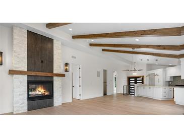 Open-concept living space with vaulted ceilings, exposed beams, fireplace, and a view into the updated kitchen at 2665 Juilliard St, Boulder, CO 80305