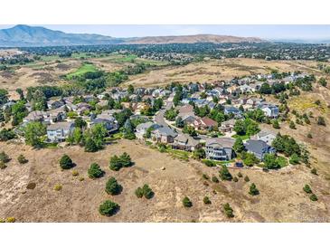 Expansive aerial view of a quiet neighborhood nestled in a landscape with rolling hills and mountain views at 10520 W Vassar Dr, Lakewood, CO 80227