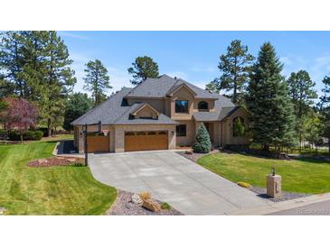 Stunning home featuring a paved driveway, basketball hoop, brick detailing and lush landscaping at 5414 Golden Currant Way, Parker, CO 80134