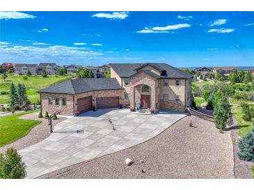 Stunning two-story home with a stone facade, lush landscaping, and a large driveway with basketball court at 7343 Upton Ct, Castle Rock, CO 80104