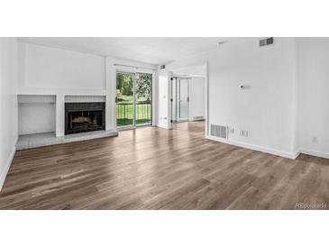 Bright living room features a fireplace and sliding glass doors to the balcony with plenty of natural light at 4899 S Dudley St # 7E, Littleton, CO 80123