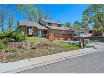 Charming brick home with a well-maintained lawn, a three-car garage, and a welcoming front porch at 128 Baylor Dr, Longmont, CO 80503