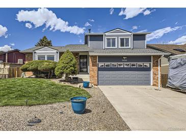 Charming home showcasing a well-maintained front yard, complemented by blue accents and a two-car garage at 3680 S Gibralter Cir, Aurora, CO 80013