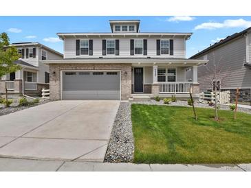 Charming two-story home featuring a brick-accented garage, covered porch, and well-manicured lawn at 7325 S Waterloo Way, Aurora, CO 80016