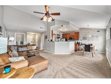 Open-concept living room featuring vaulted ceilings, plush seating, and a seamless flow into the kitchen and dining areas at 1425 Blue Sky Cir # 15-301, Erie, CO 80516