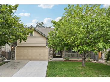 Charming home featuring a stone facade, well-maintained lawn, and a two-car garage at 8773 S Dudley St, Littleton, CO 80128