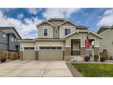 Two-story home with three-car garage, stone accents, landscaped front yard, and an American flag at 11657 Olathe St, Commerce City, CO 80022