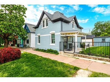 Charming two-story home with a light blue painted brick, covered porch, manicured lawn and professional landscaping at 1019 26Th St, Denver, CO 80205