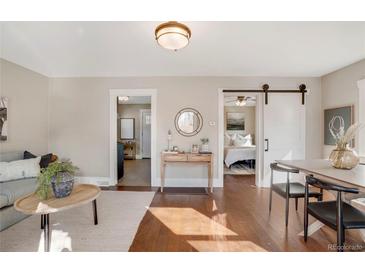 Open-concept living space with hardwood floors and views into the entry and main bedroom at 725 E Exposition Ave, Denver, CO 80209