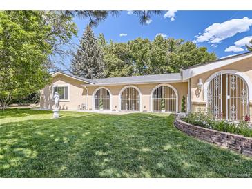 Charming house backyard with lush green grass and unique architectural arched windows at 8220 Lamar Cir, Arvada, CO 80003
