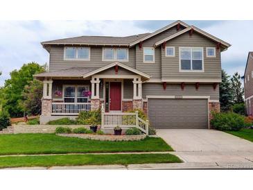 Charming two-story home with a well-maintained lawn, inviting porch, and an attached two-car garage at 14200 W 86Th Pl, Arvada, CO 80005