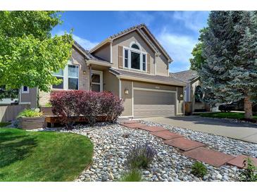 Charming exterior of a two-story home with a well-manicured lawn and stone walkway at 8258 S Reed Way, Littleton, CO 80128