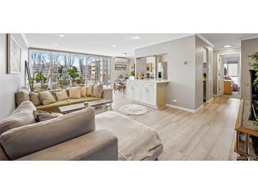 Bright living room with large windows, hardwood floors, and an open floor plan to the dining area at 955 Eudora St # 307E, Denver, CO 80220