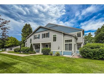 Charming townhome with blue accents, lush lawn, and mature trees under a bright blue sky at 1419 Red Mountain Dr # 126, Longmont, CO 80504