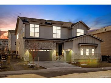 Beautiful two-story home featuring stone accents, well-lit entry, attached garage, and professionally landscaped yard at 6264 E 143Rd Dr, Thornton, CO 80602