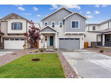 Charming two-story home features a manicured lawn, gray siding, and an attached two-car garage at 9277 Truckee Ct, Commerce City, CO 80022