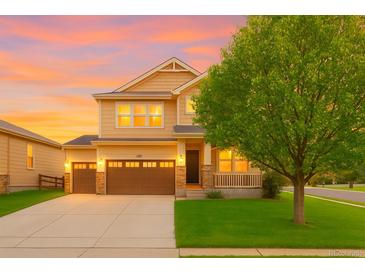 Beautiful two-story home featuring an attached garage, lovely porch, well-manicured lawn, and professional landscaping at 10995 Quintero St, Commerce City, CO 80022