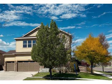Inviting two-story home with a well-maintained yard, mature trees, and a two-car garage at 10995 Quintero St, Commerce City, CO 80022