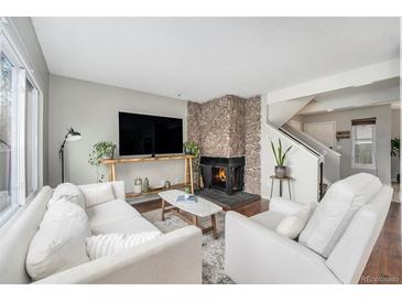 Cozy living room features a stone fireplace, modern furnishings and a large window for ample natural light at 8873 Yukon St, Broomfield, CO 80021