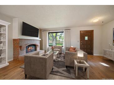 Comfortable living room with modern furnishings, a brick fireplace, and a large window at 14735 W Ellsworth Ave, Golden, CO 80401
