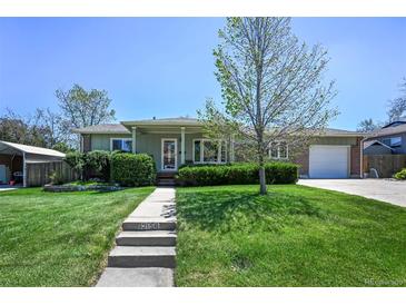 Charming home featuring a well-manicured front yard, lush lawn, and a welcoming walkway leading to the front door at 12154 W Exposition Dr, Lakewood, CO 80228