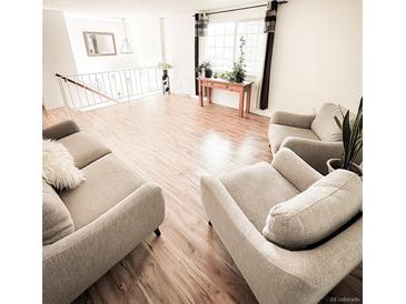 Bright living room with hardwood floors, contemporary furniture, and large windows at 357 Saturn Pl, Lone Tree, CO 80124