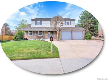 Charming two-story home boasts an inviting front porch, a manicured lawn, and a two-car garage at 7405 S Jackson Ct, Centennial, CO 80122