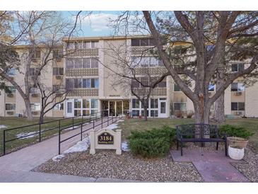Three-story building with mature trees, a bench, and a walkway leading to building 212 at 3184 S Heather Gardens Way # 406, Aurora, CO 80014