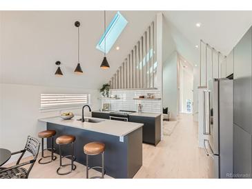 Bright kitchen boasts skylight, sleek cabinetry, island with seating, and stainless steel refrigerator at 1101 S Dahlia St, Denver, CO 80246