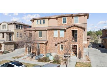 Charming townhome exterior featuring a mix of brick and stucco finishes with a small front yard at 9374 Loggia St # D, Highlands Ranch, CO 80126