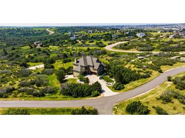 Stunning aerial view of a tan home on a spacious lot with mature landscaping and winding driveway, surrounded by green space at 4320 Stone Post Dr, Castle Rock, CO 80108